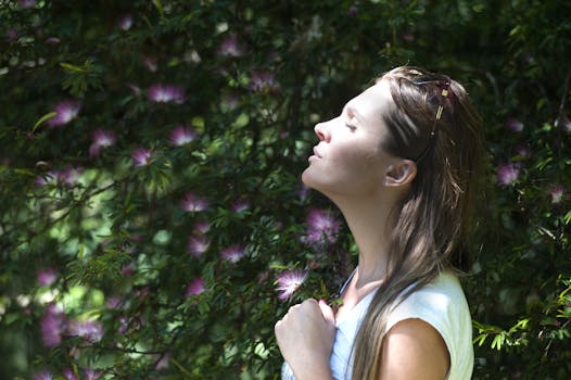 A woman enjoying a mindfulness moment in a sunlit garden, surrounded by vibrant flowers.