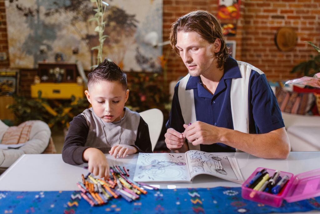 Mindful Parenting; Child engaged in coloring activity at home with adult supervision, fostering creativity.