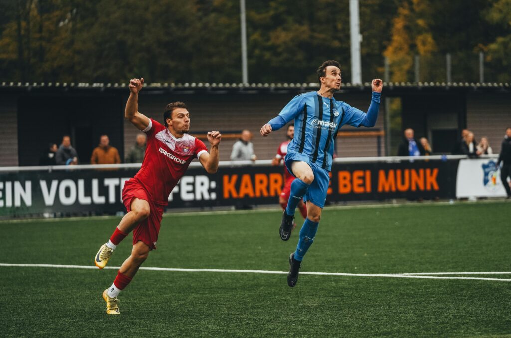Two soccer players in action during a competitive match on a green field.