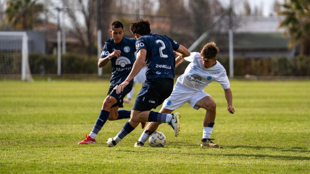 Intense soccer game between two teams in blue and white jerseys on a grassy outdoor field.