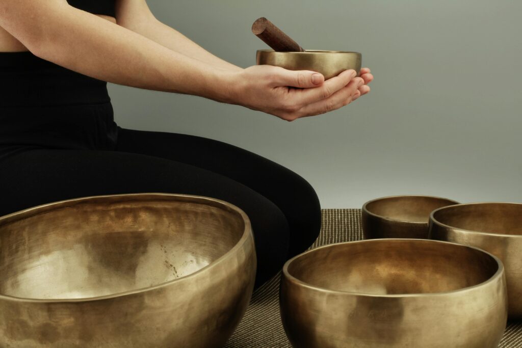 A person using bronze singing bowls for meditative sound therapy in a calm setting.