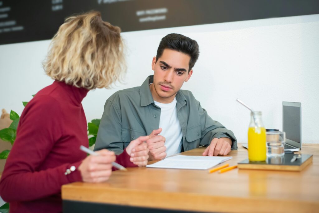 Two young adults engaged in conversation at a café, focused on a document.