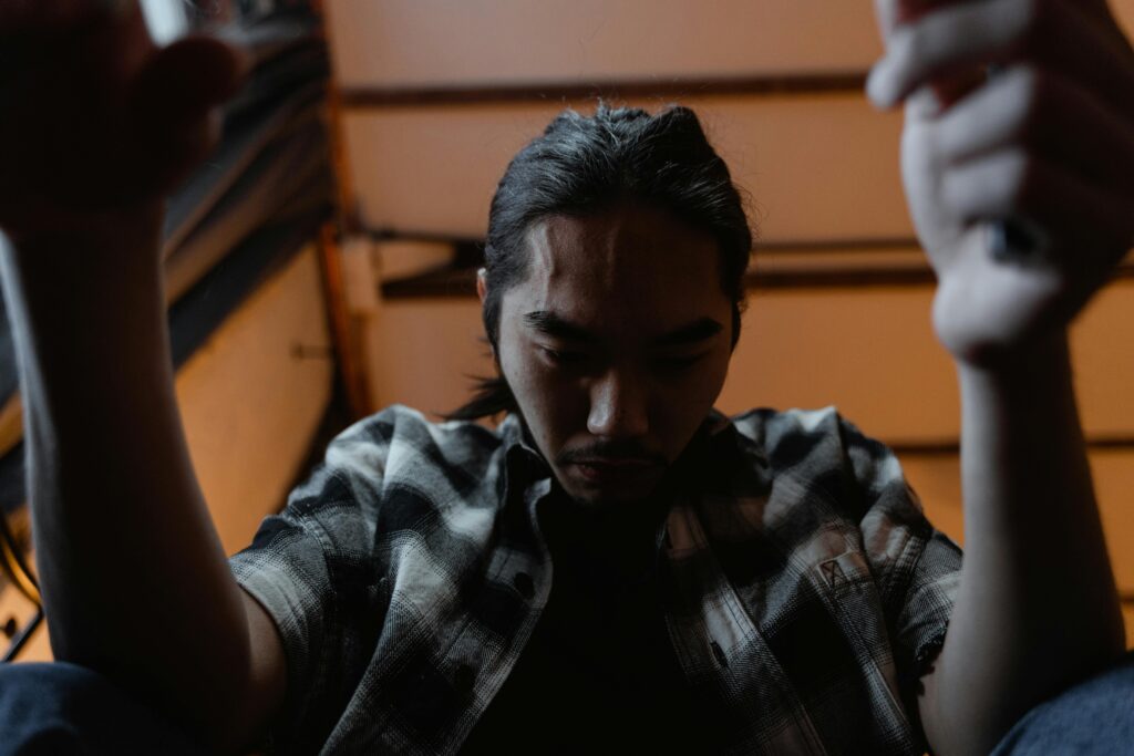 A young man sitting indoors, expressing deep emotion and contemplation.